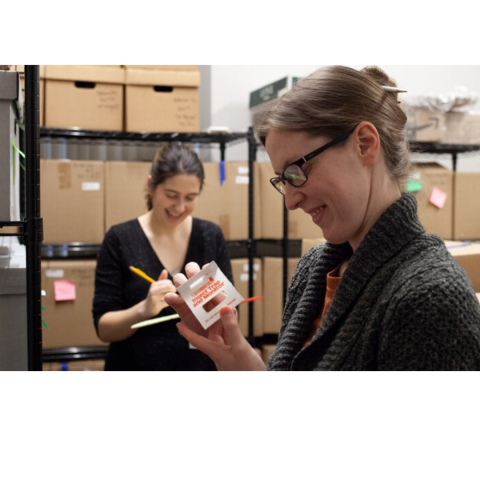 two woman working on labeling items in library archive