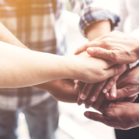 A group of people joining their hands together in a sign of unity and teamwork