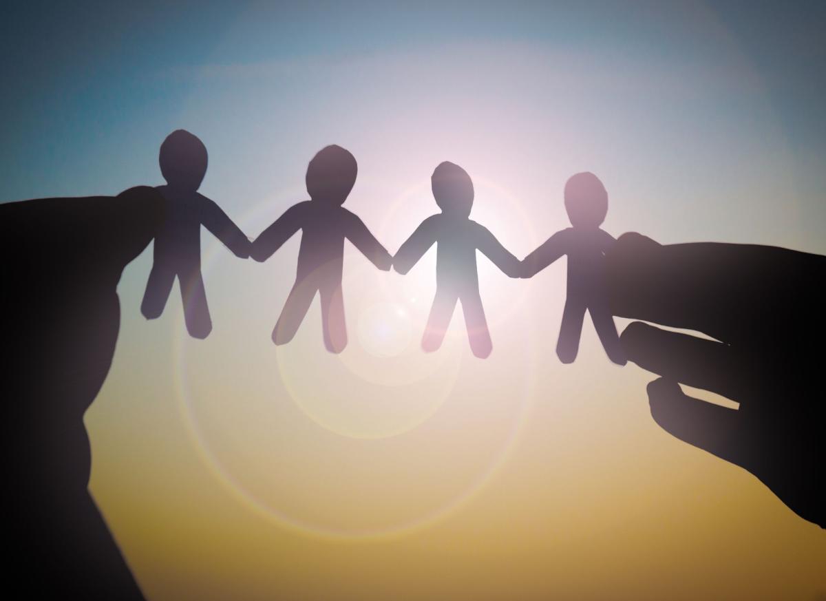 two hands holding up a string of connected paper dolls