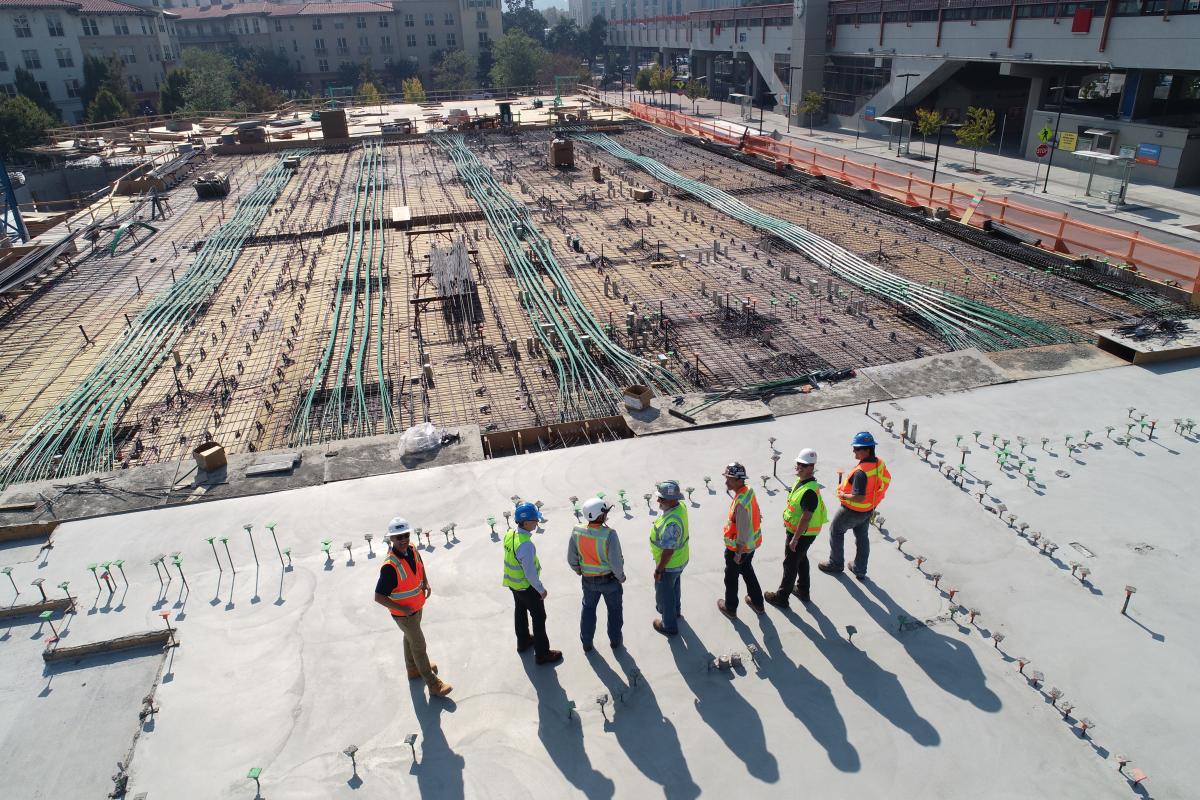 seven construction works standing on newly constructed building foundation