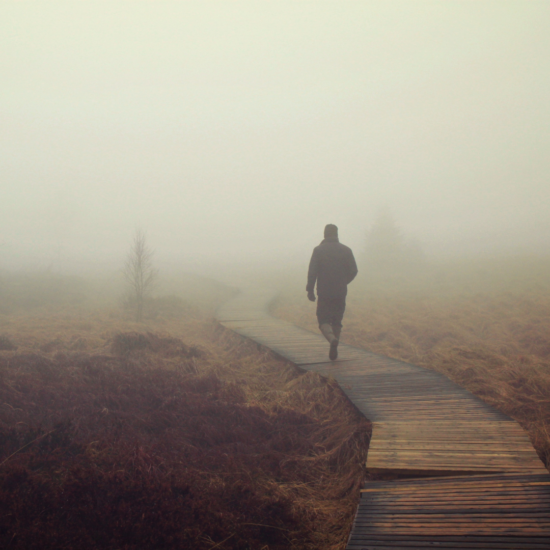 man walking on bridge in the fog