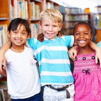 three children standing together with arms around each other with library stacks in the background